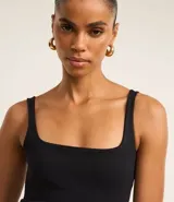 Vestido midi negro de punto roma, con escote cuadrado y corte ajustado. Incluye cinturón ancho de cuero negro con hebilla dorada.