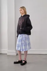 Buzo negro con capucha y cordón ajustable, con estampado de dos caballos y una estrella en color naranja. Tiene un bolsillo tipo canguro en la parte delantera.