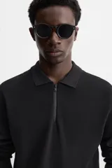 Polo negro de punto con cuello solapa y cierre frontal de cremallera.