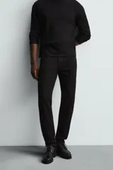 Pantalón de jean negro, corte slim fit, con tiro medio, cinco bolsillos, efecto lavado y cierre frontal con cremallera y botón.