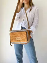 Bandolera de cuero color tostado con textura tipo cocodrilo en la parte frontal. Tiene correa larga regulable y cierre con cremallera.