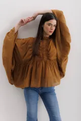 Camisa color marrón con cuello mao, mangas largas abullonadas y detalle de volados en el frente.