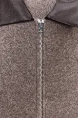 Chaqueta de punto color marrón claro con cuello solapa a contraste en simil cuero color marrón oscuro y manga larga. Cierre frontal con cremallera metálica.