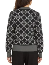 Sweater azul marino con diseño de rombos blancos con el logo de la marca en el centro. Tiene cuello redondo, puños y bajo acanalados.