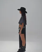 Short de jean negro con terminaciones desflecadas y cinturón de cuero negro con argollas plateadas.