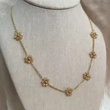 Collar dorado con cadena de acero y cristales color champagne en forma de flor.