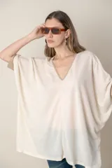 Blusa italiana color crema, tipo poncho, con escote en V con lurex, mangas 3/4 y puños ajustados.