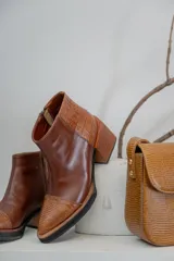 Bota corta de cuero color marrón con textura reptil, caña baja, cierre lateral y taco ancho.