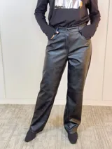 Pantalón negro de eco cuero, corte recto y tiro alto.