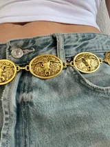 Cinturón plateado tipo cadena con dijes ovalados con diseño de toro.
