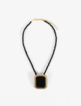 Collar con cordón negro trenzado y dije cuadrado con borde dorado y centro negro.