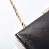Sobre negro de simil cuero, con cierre metálico y cadena, diseño elegante.