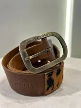 Cinturón de cuero con estampado animal print de vaca, hebilla metálica dorada y reverso de cuero color bordó.