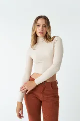 Polera color beige de corte crop, cuello alto y mangas largas.
