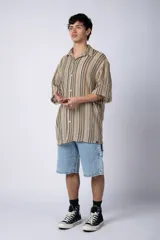 Camisa de manga corta con cuello solapa, corte holgado y estampado de rayas verticales en tonos beige, negro y rojo.