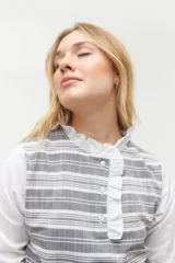 Blusa rosada con mangas largas, cuello con volados y estampado de líneas verticales.
