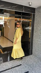 Vestido largo color amarillo pálido, con escote en V, mangas cortas abullonadas con detalle de calado y ruedo con volantes y calado.