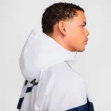 Campera deportiva Nike Windrunner para hombre, color blanco y azul marino, con capucha y logo de Nike bordado en el pecho.