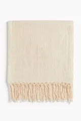 Chal color crema en tejido liviano de lino y algodón con flecos en los extremos.