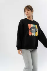 Buzo negro de algodón rústico con estampa frontal multicolor de labios. Corte relajado, cuello redondo y terminaciones en rib.