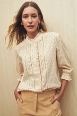 Camisa blanca de manga 3/4 confeccionada en algodón liviano con diseño calado y detalles de encaje en el frente. Cuello con volados.