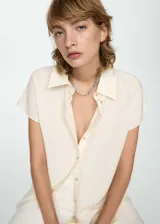 Camisa color crema de manga corta, con cuello camisero y cierre frontal con botones.