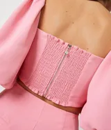 Blusa cropped color rosa con escote cuadrado y mangas cortas abullonadas.