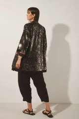 Saco largo abierto de crepe color negro con bordado de lentejuelas, canutillos y mostacillas plateadas. Tiene mangas largas, cuello redondo, bolsillos delanteros y forrería de jacquard a tono.