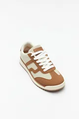 Zapatillas beige con recortes en gamuza de diferentes tonos, cordones y suela irregular blanca con detalle rosa.