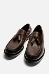 Mocasín de vestir color marrón oscuro, con detalle de borlas en la parte delantera.