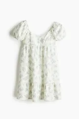 Vestido corto blanco con estampado de flores azules, escote corazón, mangas cortas abullonadas con elástico en hombros y puños, espalda fruncida, corte ajustado en el busto y falda con vuelo y costura fruncida en el bajo.