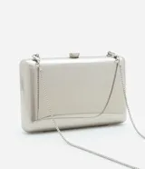 Cartera clutch rectangular rígida color dorado, con textura acanalada y cierre de broche. Incluye correa de cadena dorada desmontable.