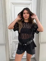 Remerón negro de encaje con mangas cortas, cuello redondo y corte holgado. Incluye un cinturón con apliques metálicos.