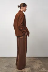 Pantalón de tiro medio confeccionado en hilatura de lino 100%. Cintura con elástico en espalda ajustable con cordones. Bolsillos laterales ocultos en costura y de plastrón en espalda.