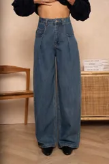 Pantalón de jean azul de corte holgado, con cintura alta, bolsillos delanteros y traseros, y pliegues en la parte superior de las piernas.