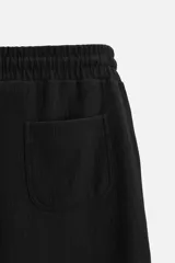 Bermuda negra de corte relaxed fit, con cintura elástica ajustable con cordón, bolsillos frontales y bolsillo trasero de parche.