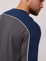 Remera de hombre azul marino con mangas y cuello amarillo, y logo de la marca Rusty estampado en el pecho.