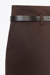 Pantalón marrón de tiro alto con cinturón negro, bolsillos delanteros y cierre frontal con cremallera y gancho metálico.