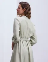 Vestido maxi color beige, con cuello mao, mangas 3/4 con presilla y lazo en la cintura.