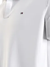 Chomba blanca de felpa de Tommy Hilfiger con cuello clásico, corte amplio, logo bordado en el pecho y detalles distintivos de la marca.