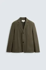 Blazer color verde militar de algodón con efecto lavado, corte relaxed fit, cuello con solapas de muesca, manga larga, bolsillos frontales de plastrón y cierre frontal con botonadura.