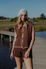 Conjunto tejido de algodón color celeste con terminaciones en marrón. Incluye un top sin mangas con botones y un short de tiro alto.