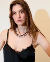 Top negro estilo lencero con escote en V, puntilla de encaje y breteles finos. La espalda es baja con un recorte de gasa que genera transparencia.