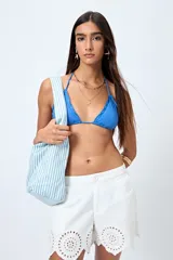 Top de bikini blanco con tirantes finos ajustables al cuello y a la espalda. Presenta volados en el escote y está confeccionado en tejido suave con acabado elástico.