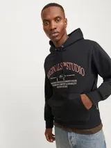 Canguro negro con capucha y cordones ajustables, de manga larga y corte relajado. Estampado frontal con texto "ORIGINALS MSTUDIO" en color ladrillo.