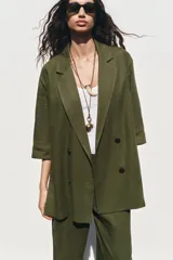 Blazer color verde oliva confeccionada en lino, con cuello solapa, manga tres cuartos con vuelta y cierre cruzado con botones.