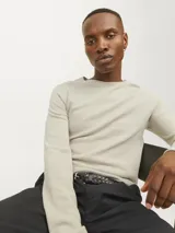 Sweater de punto color beige claro, de manga larga y cuello redondo.