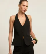 Chaleco negro con frente única, corte peplum, estructura sastre y cierre frontal con botones.