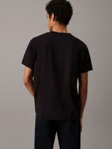 Remera negra de manga corta con cuello redondo y logo Calvin Klein Jeans estampado en el pecho con efecto brillante.