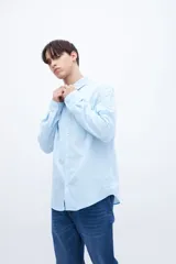 Camisa celeste de algodón, corte regular fit, con cuello solapa clásico, manga larga, bolsillo en el pecho y botones personalizados.